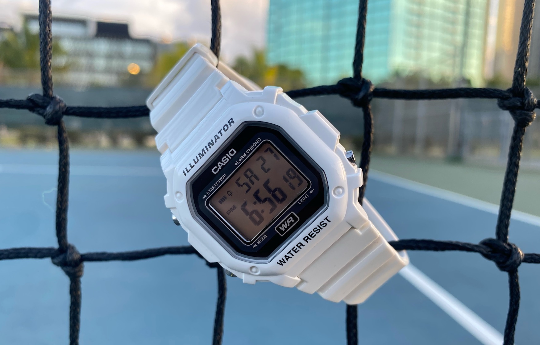 ساعت کاسیو مربعی سفید رنگ در کنار زمین تنیس