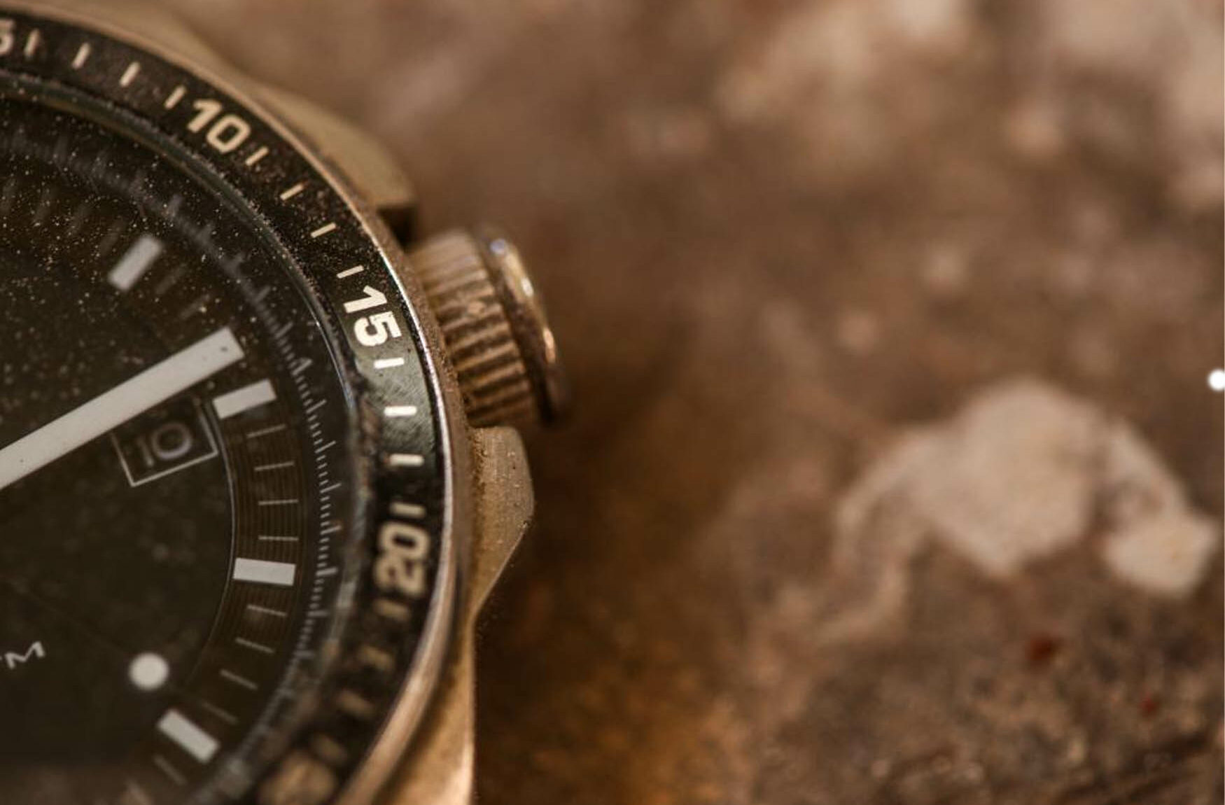 صفحه ساعتی فرسوده که تا حدی در پس‌زمینه خاک قابل مشاهده است